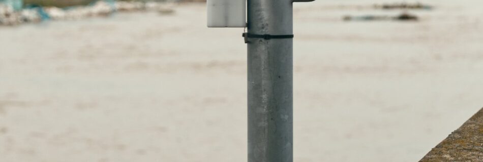 An Obscape monitoring station on a pole above a swollen, sediment-laden river