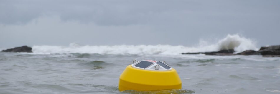 An Obscape OBS-Buoy 7 Watt floating at sea with surf breaking on rocks behind