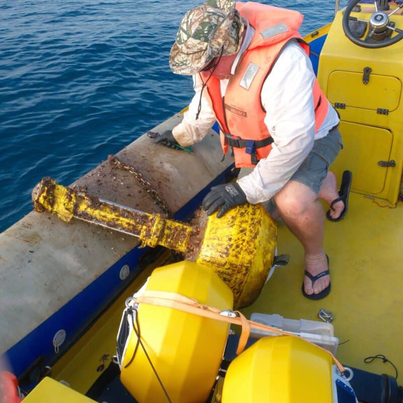 A field technician on a boat retrieving Obscape offshore monitoring instruments from the sea